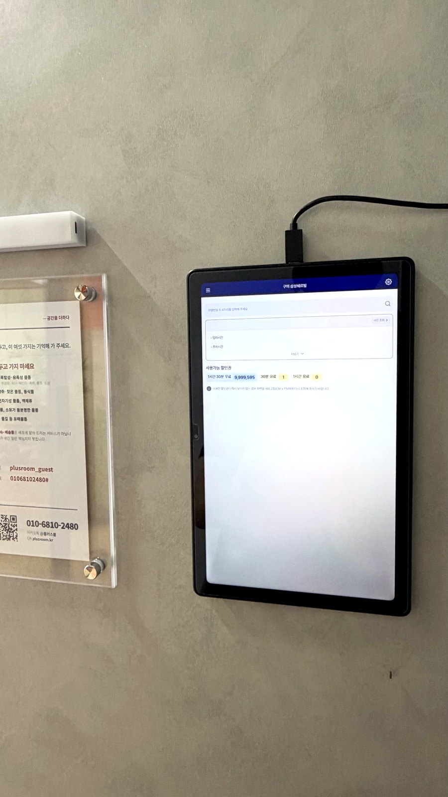 창고 입구 벽면에 설치된 주차 등록 키오스크 — 차량번호를 입력하는 태블릿 화면