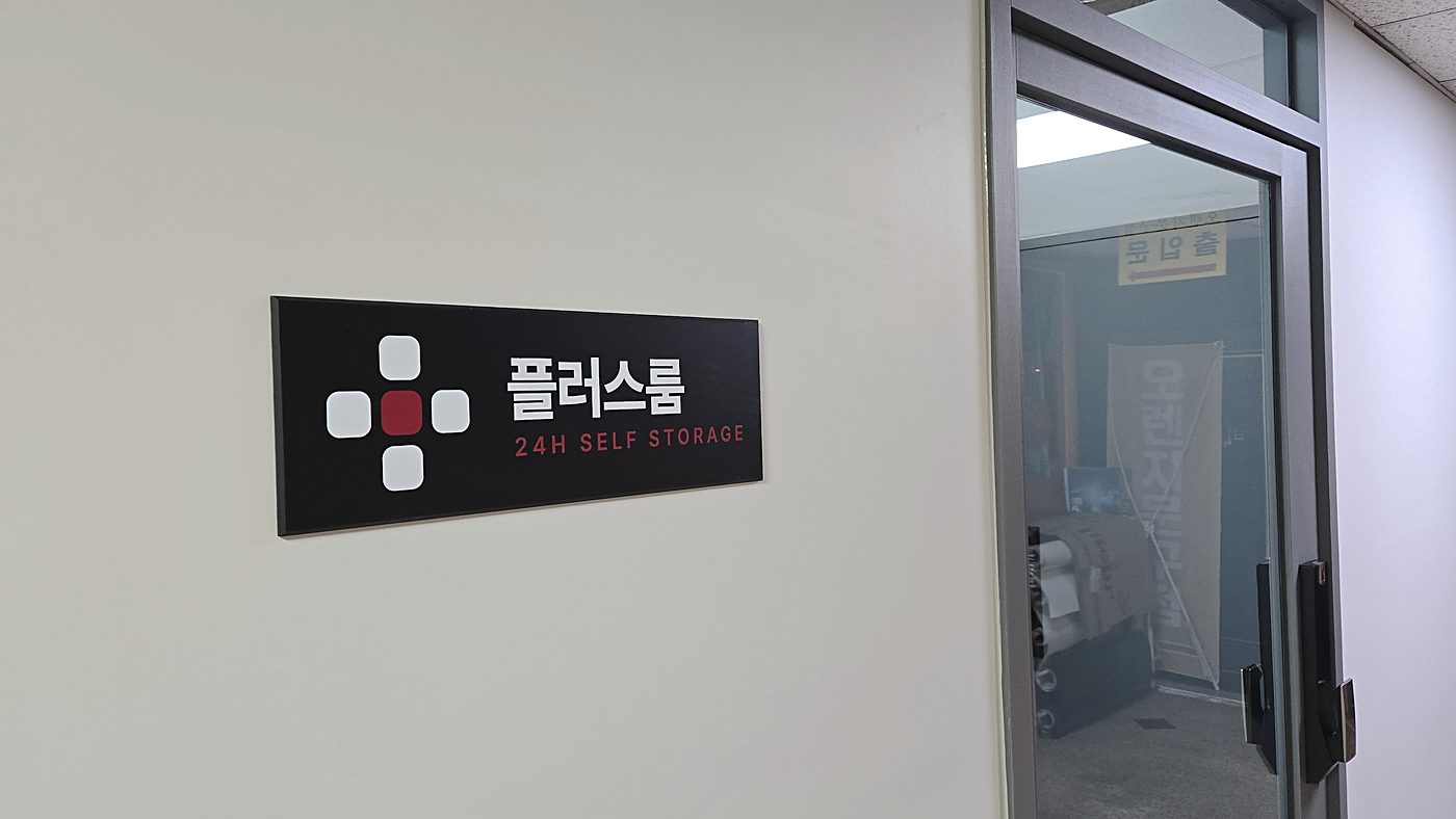 107호 입구 벽면의 플러스룸 간판